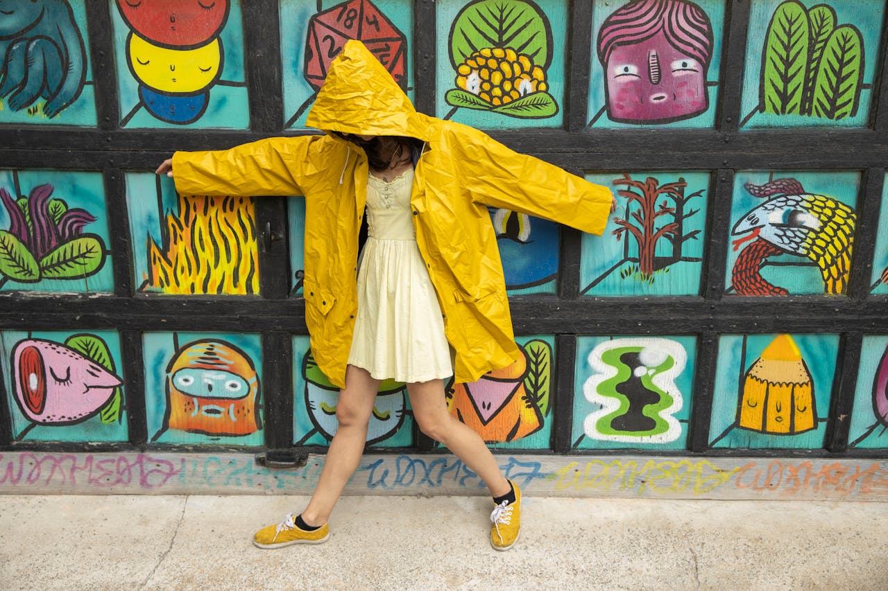 Woman in a yellow raincoat poses against a vibrant mural wall in Montréal.
